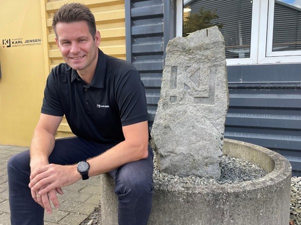 Dennis Thisted Tordrup fra A/S Karl Jensen - et medlem af Mariagerfjord Erhverv, poserer smilende på en cementbeholder.