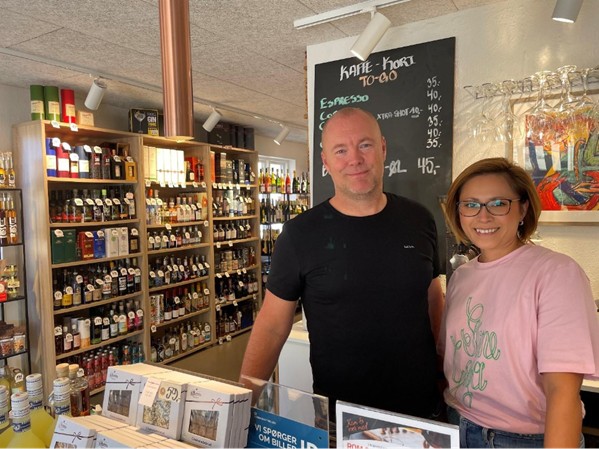 Cille og Tom Kristensen fra Vinspecialisten - et medlem af Mariagerfjord Erhverv - poserer og smiler til kameraet i deres forretning i Mariager.
